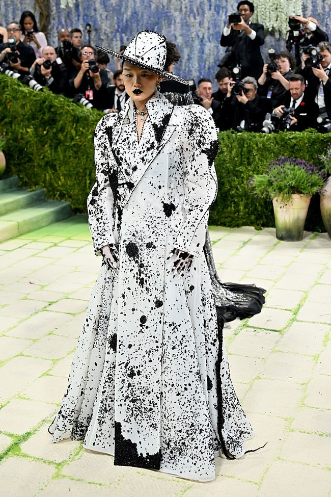 Selain EJAE, ada Audrey Nuna yang eksis mengisi soundtrack KPop Demon Hunters di MET Gala 2026. Berbalut mantel putih dengan aksen cipratan cat hitam rancangan Robert Wun, serta topi fedora berdesain serupa. Gayanya semakin dramatis dengan lipstik hitam pekat dan rambut kepang panjang menyentuh lantai. Foto: Getty Images