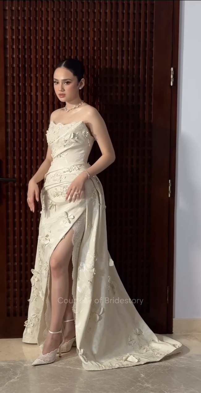 Gaun yang tampil dalam nuansa ivory champagne ini terlihat elegan dan feminin dengan siluet strapless serta potongan fitted yang membentuk tubuh lalu melebar menjadi rok dengan train panjang di bagian belakang. Terdapat belahan yang cukup tinggi pada bagian depan, memperlihatkan kaki sekaligus memberi kesan sensual namun tetap classy. Ia juga melengkapi penampilannya dengan heels senada dari Jimmy Choo yang harganya ditaksir capai Rp 35,2 juta. Foto: Instagram/@thebridestory
