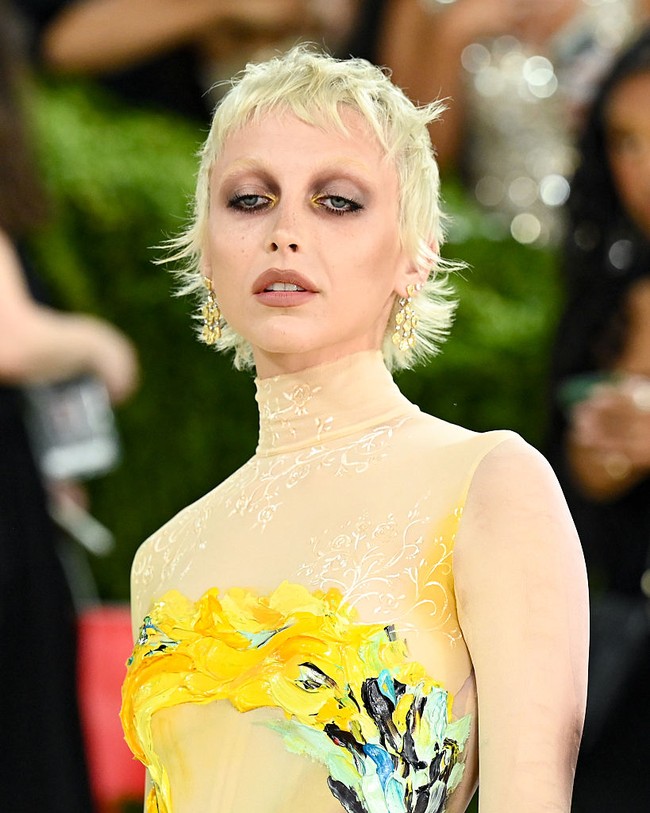 Makeup Emma Chamberlain berfokus pada riasan mata, di mana warna mauve dan plum dilayer dengan sentuhan kuning yang memberi dimensi unik. Bleached eyebrow juga memberikan kesan unik pada penampilannya.  Foto: Getty Images/Jamie McCarthy