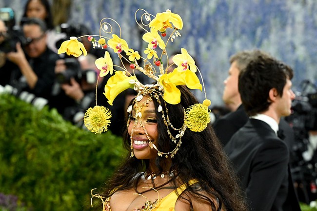 SZA tampil dengan permainan warna yang terlihat sederhana, tapi sebenarnya cukup berani. Ia mengusung palet emas dan pink senada dengan busananya, yang diterjemahkan lewat eyeshadow kuning cerah di kelopak mata, dipadukan dengan blush dan lip bernuansa rosy yang lembut.  Foto: Getty Images/Jamie McCarthy