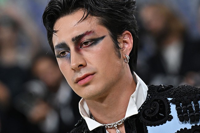 Hudson Williams membawa glam makeup pria ke level terdepan. Perpaduan eyeshadow biru dan merah berkilau dengan winged liner hitam yang tegas terlihat berani. Ia menyebut film Black Swan sebagai inspirasi utamanya.  Foto: Getty Images/Jamie McCarthy