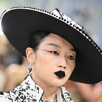 Audrey Nuna menghadirkan makeup yang nyaris seperti karya seni abstrak. Kulit dibuat pucat dan dewy agar fokus pada bibir berhias rhinestone hitam serta graphic liner yang tidak simetris. Foto: Getty Images/Jamie McCarthy