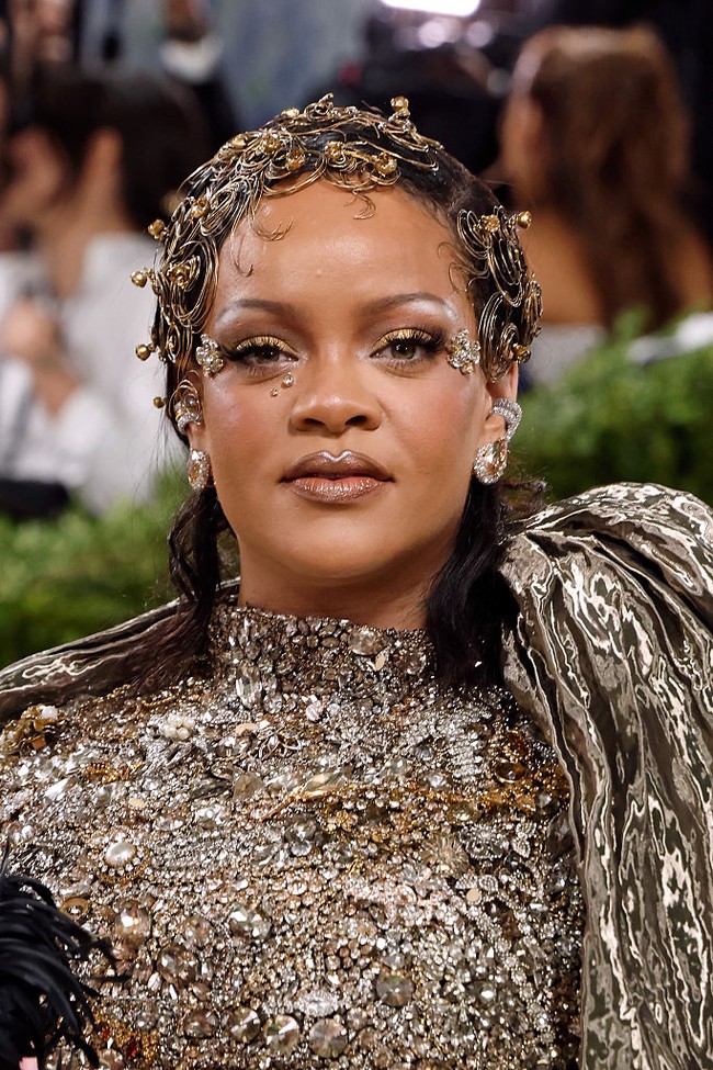 Tak lengkap rasanya Met Gala tanpa momen ikonik dari Rihanna. Tahun ini, ia tampil dengan metal pin curls yang tampak seperti perhiasan rambut. Makeup-nya fokus pada golden glow dengan sentuhan kristal di area mata. Foto: Getty Images/Jamie McCarthy