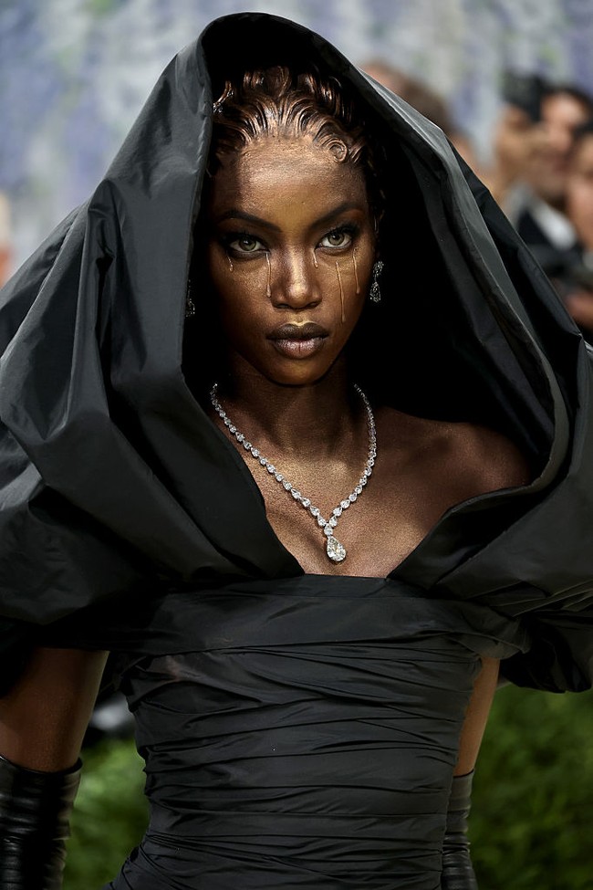 Supermodel Anok Yai tampil layaknya patung hidup. Kulitnya terlihat berkilau dengan efek gilded, dilengkapi detail teardrops bertekstur dan finger waves berlapis emas. Dari kepala hingga décolletage, semuanya terasa sangat terkonsep. Foto: Getty Images/Jamie McCarthy