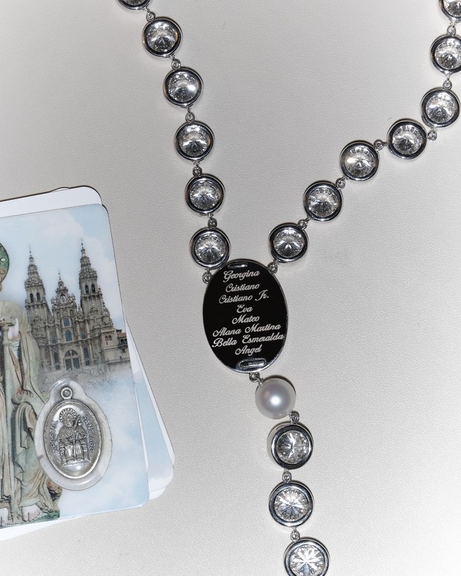 Tampilannya juga dilengkapi rosario yang dibuat khusus oleh Chopard menggunakan emas putih dan dihiasi dengan berlian dan mutiara serta diukir dengan nama anggota keluarga model juga pengusahan tersebut.Foto: Instagram @georginagio