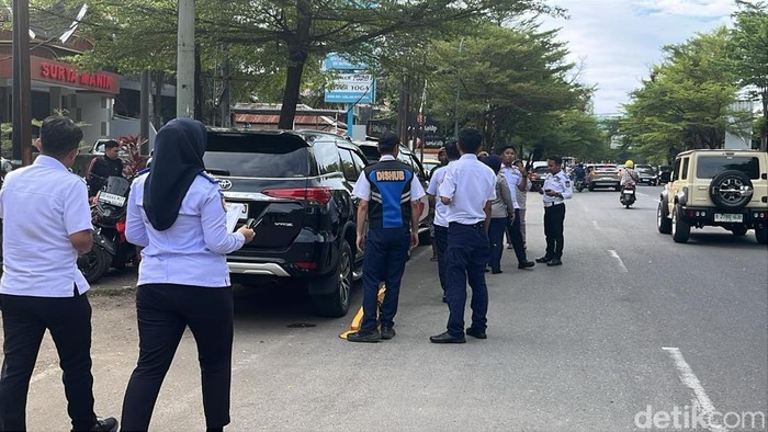 Petugas Dishub Makassar menggembok mobil yang parkir liar di Jalan Ratulangi.