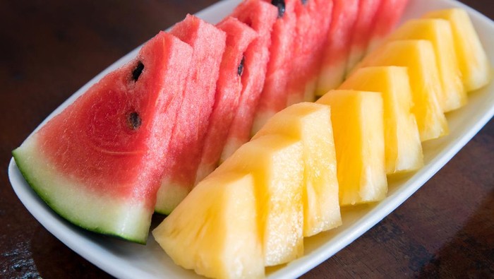 Watermelon and pineapple slices on a wood ceramic plate