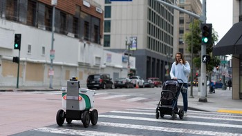 Robot pengantar makanan otonom melintas di samping seorang pria yang mendorong stroller di pusat kota Los Angeles, California, Amerika Serikat, Jumat (1/5/2026). REUTERS/Mike Blake