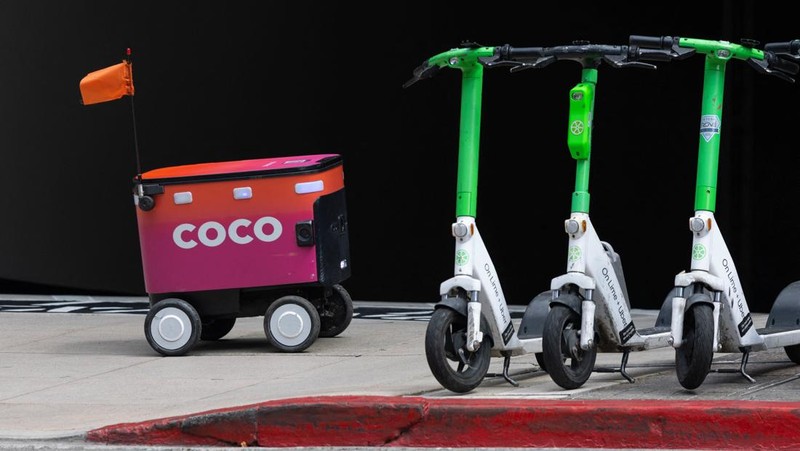 An autonomous food delivery robot passes a pod of electric scooters in downtown Los Angeles, California, U.S., May 1, 2026.  REUTERS/Mike Blake