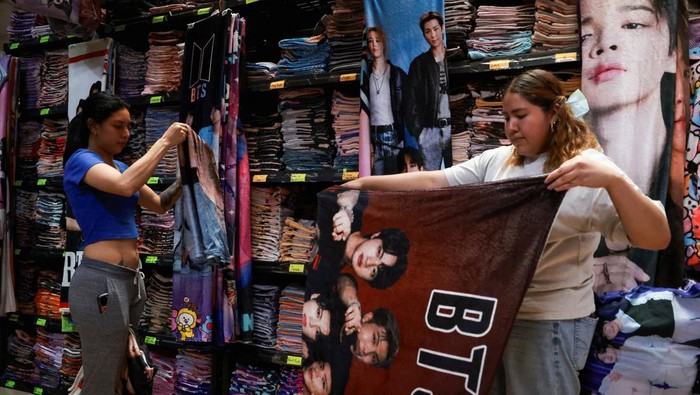 A vendor walks beside blankets featuring South Korean Kpop boy band BTS hanging for sale in a shop ahead of concerts on the BTS world tour 