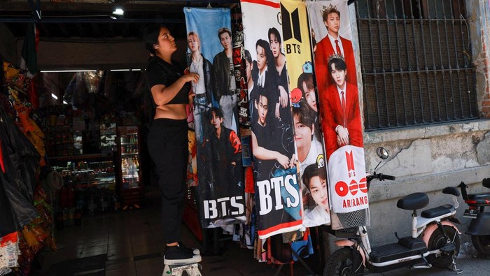 A vendor walks beside blankets featuring South Korean Kpop boy band BTS hanging for sale in a shop ahead of concerts on the BTS world tour 