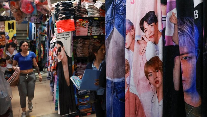 A vendor walks beside blankets featuring South Korean Kpop boy band BTS hanging for sale in a shop ahead of concerts on the BTS world tour 