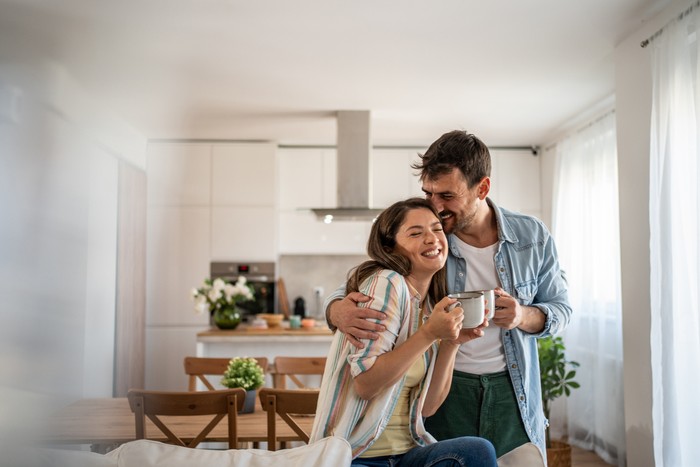 Young couple drinking morning coffee enjoying the weekend in their new apartment