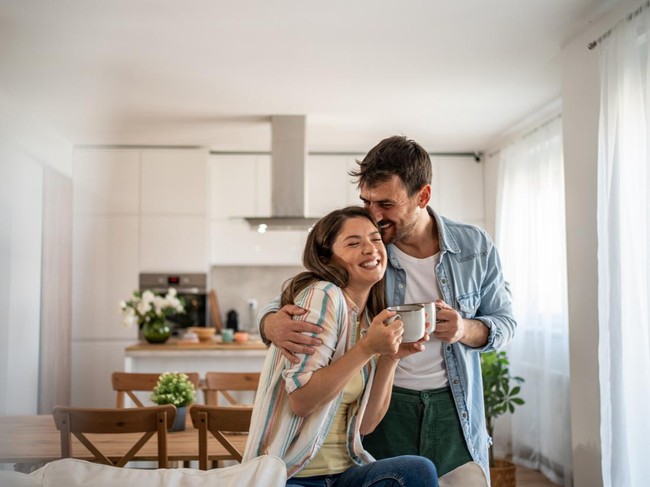 Young couple drinking morning coffee enjoying the weekend in their new apartment