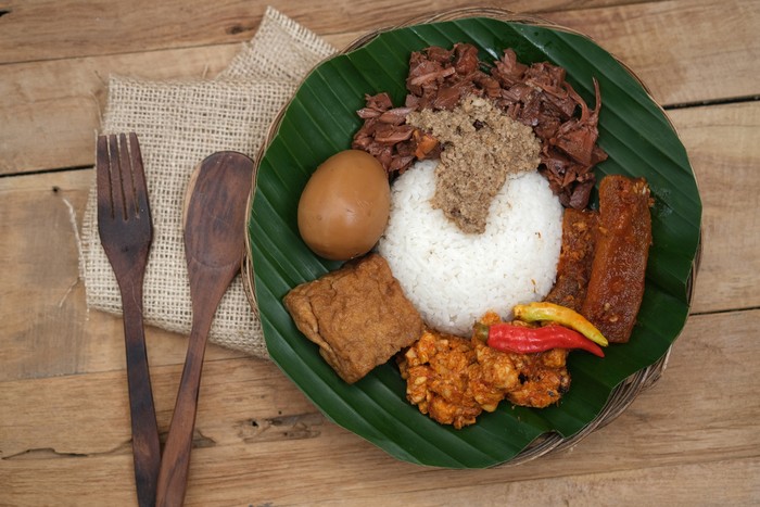Nasi Gudeg Krecek is rice and gudeg, which is made from processed young jackfruit, coconut milk, spices, tofu, eggs and chicken. Yogyakarta specialties. Indonesian food. Served with banana leaves.