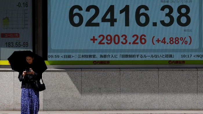Pasar Jepang Bergairah, Nikkei Tembus Rekor Pedestrians walk past a stock quotation board showing the Nikkei share average outside a brokerage in Tokyo, Japan, May 7, 2026. REUTERS/Kim Kyung-Hoon