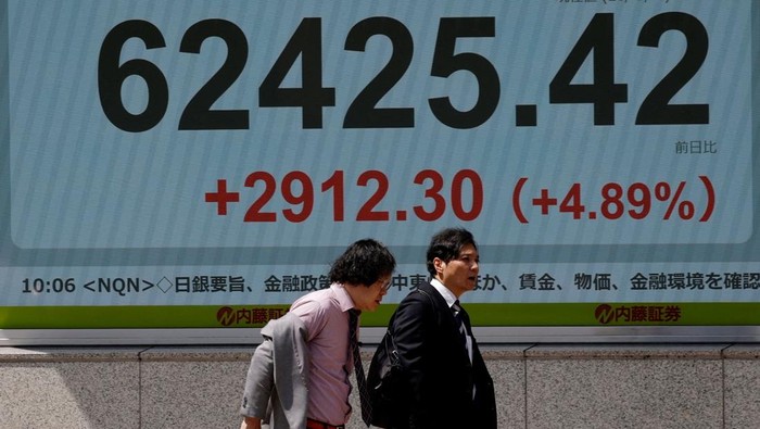 Pasar Jepang Bergairah, Nikkei Tembus Rekor Pedestrians walk past a stock quotation board showing the Nikkei share average outside a brokerage in Tokyo, Japan, May 7, 2026. REUTERS/Kim Kyung-Hoon