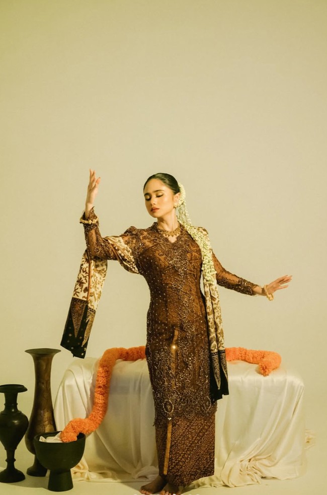 Penampilannya juga dilengkapi dengan selendang batik bernuansa cokelat hangat dengan aksen prada emas yang melambangkan keteguhan hati serta semangat meraih cita-cita. Selendang tersebut memberi efek visual dramatis sekaligus memperkuat nuansa tradisional Nusantara pada pemotretan. Foto: Instagram/@tissabiani