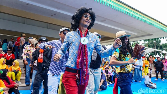 Warga kompak mengenakan pakaian jadul dalam kegiatan Nyedengin Baju pada rangkaian Lebaran Depok 2026 di Alun-alun Kota Depok, Kamis (7/5/2026). Mereka berjalan di atas karpet biru sambil menampilkan gaya khas tempo dulu yang menarik perhatian pengunjung.d