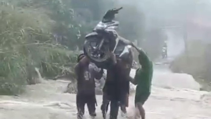 Warga di Enrekang, Sulawesi Selatan (Sulsel) gotong motor melewati jalan yang terendam banjir.