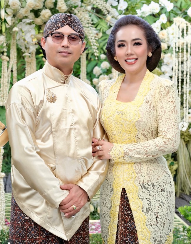 Bawahannya memakai kain batik bernuansa cokelat tua dengan motif tradisional Jawa yang serasi dengan suami, Herwan Prandoko. Melengkapi penampilannya, Soimah juga mengenakan aksesori emas yang klasik. Seperti anting bulat di kedua telinga, serta cincin. Foto: Instagram/@showimah