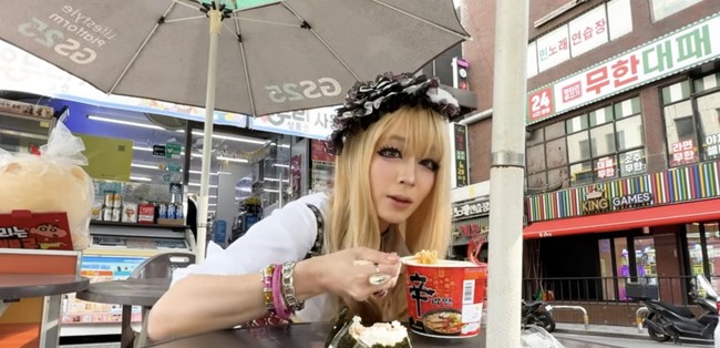 Setelah menjalani proses makeup yang cukup lama, Lee Min Jung mampir ke minimarket karena lapar untuk membeli mie cup instan dan onigiri. Gaya nyentriknya membuat netizen yang berlalu-lalang terkejut hingga nyaris tersandung. Foto: dok. YouTube @Rheeminjung_MJ