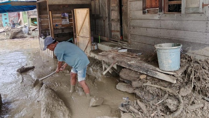 Warga Aceh Tenggara membersihkan rumahnya yang berlumpur akibat banjir bandang (Foto: BPBA)