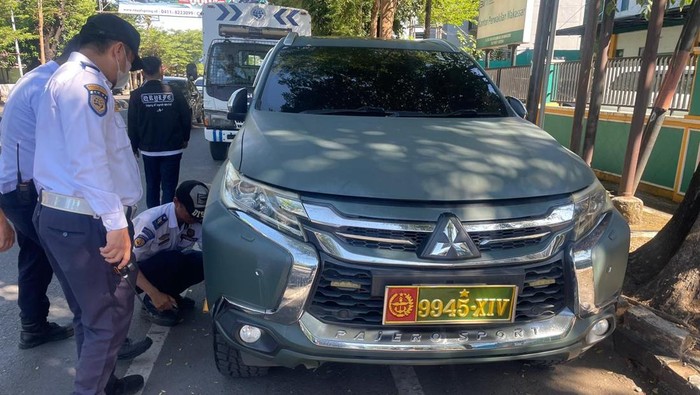 Petugas Dishub Makassar menggembok mobil yang parkir liar di badan jalan.
