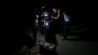 Warga memperbaiki sepeda motor dengan penerangan minim saat pemadaman listrik di Valencia. Reuters melaporkan sejumlah wilayah di Venezuela kini mengalami pemadaman bergilir hingga berjam-jam setiap hari akibat menurunnya kapasitas pasokan listrik nasional. REUTERS/Juan Carlos Hernandez