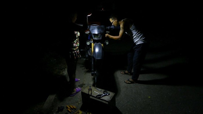 A barber works during a blackout using electricity from a fuel-powered backup generator, as Venezuelans face increasing power cuts due to the country's deteriorated grid, in Valencia, Venezuela May 9, 2026. REUTERS/Juan Carlos Hernandez