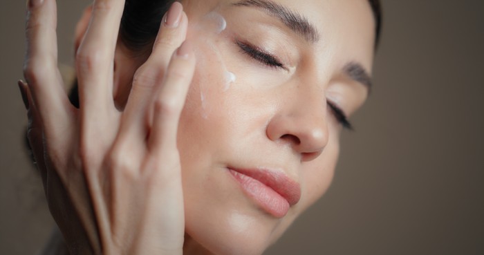 Skincare, face cream and woman with natural, moisturizing or collagen facial treatment. Beauty, grooming and female person with dermatology routine with spf, sunscreen or lotion by studio background