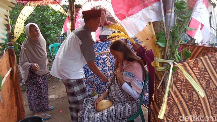 Seorang ayah di Indramayu melakukan tradisi memitu, menyiram anaknya, ibu hamil tujuh bulan, dengan air kembang yang telah didoakan.