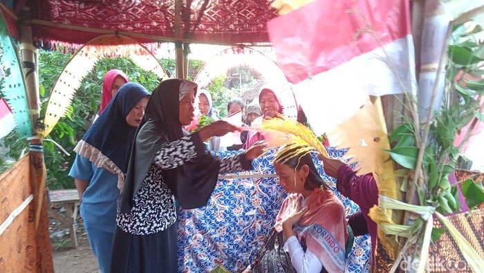 Seorang ibu menyiram anaknya (ibu hamil tujuh bulan) dengan air kembang yang sudah didoakan dalam tradisi memitu di Indramayu