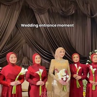 Paduan hijab yang sleek ini sengaja dibuat minimalis tanpa banyak lilitan untuk memberikan sorotan penuh pada mahkota dan detail payet rumit serta rumbai manik-manik yang menghiasi kerah tinggi gaun pernikahannya. Para bridesmaid dari Modinity Group kompak memakai busana serba merah yang memesona. Foto: Dok. Instagram @thepotomoto.