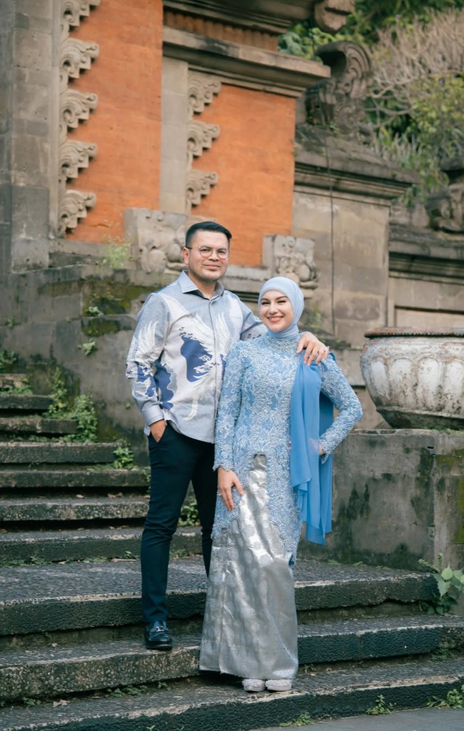 Penampilan Irish tampak serasi dengan suaminya, Haldy Sabri, yang mengenakan kemeja motif artistik bernuansa abu-abu, putih, dan biru. Kemeja tersebut dipadukan dengan celana hitam slim fit dan sepatu loafers hitam. Foto: Instagram/@_irishbella_