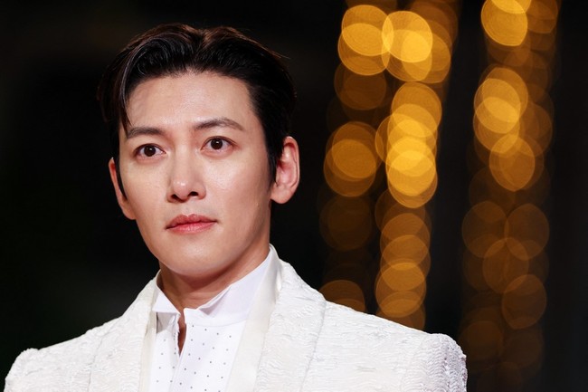 Lawan main Jun Ji Hyun, Ji Chang Wook, tampil elegan dalam setelan jas dari koleksi Tom Ford. Bintang drakor ‘The Manipulated’ ini memadukan jas bertekstur dengan kemeja putih, celana hitam dan syal tipis yang disampirkan di leher. Foto: AFP/SAMEER AL-DOUMY