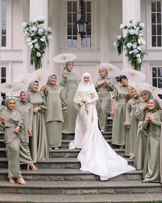 Berdiri di antara para pengiringnya sesama desainer Modinity Group, hijab putih bersih Indah Nada Puspita tampil kontras dan menjadi pusat perhatian utama. Gaya hijabnya yang modern dan timeless berpadu serasi dengan keselarasan warna hijau sage dari seragam para bridesmaids. Foto: Dok. Instagram @thepotomoto.