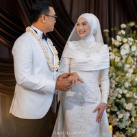 Gaya hijab Indah Nada Puspita menampilkan siluet yang rapi dan clean look yang menutup leher dengan sempurna. Dipadukan dengan veil brokat panjang yang menjuntai indah, hijab ini sukses memberikan kesan pernikahan modern yang mewah dan berkelas. Foto: Dok. Instagram @thepotomoto.