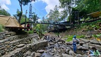 Anak-anak hingga orang dewasa tampak turun ke aliran sungai dangkal sambil menikmati suasana sejuk khas pegunungan.