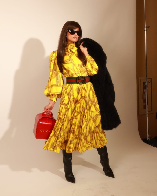 Pengusaha, DJ, sekaligus sosialita ini mengenakan gaun midi lengan panjang berwarna kuning neon. Gaun dengan aksen lipit ini hadir dengan motif hardware horse bit Gucci yang ikonik. Foto: Instagram/@parishilton