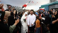 Pasangan pengantin tampak mengenakan pakaian resmi saat tiba di area acara. Mereka disambut di tengah suasana perayaan yang berlangsung meriah. Majid Asgaripour/WANA via REUTERS