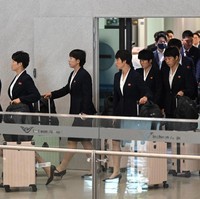 Sejak keluar dari area kedatangan bandara, para pemain langsung mencuri perhatian. Mereka terlihat mengenakan blazer gelap dan rok sepanjang lutut dengan model serupa, lengkap dengan koper warna pink yang sama.  Foto: AFP/JUNG YEON-JE