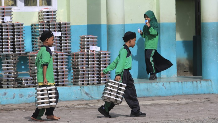 Sejumlah siswa membawa ompreng Makan Bergizi Gratis (MBG) di komplek Madrasah Ibtidayyah Negeri (MIN) 11 Aceh Barat dan Madrasah Tsanawiyah Swasta (MTS) Harapan Bangsa Desa Kuta Padang, Johan Pahlawan, Aceh Barat, Aceh, Rabu (20/5/2026). Pemerintah m