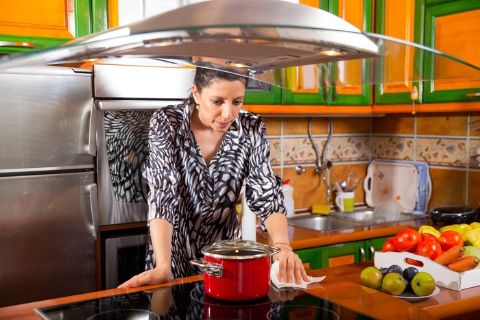 Wanita bersih-bersih sambil memasak