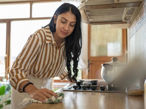 Wanita bersih-bersih sambil memasak
