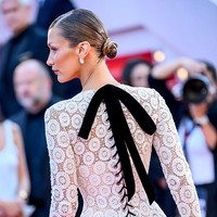 Bagian belakang menawarkan daya tarik tersendiri lewat dekorasi pita dan simpul tali atau lacing bergaya korset. Model sekaligus aktris itu juga menyempurnakan gayanya dengan perhiasan mutiara. (Foto: Lionel Hahn/Getty Images)