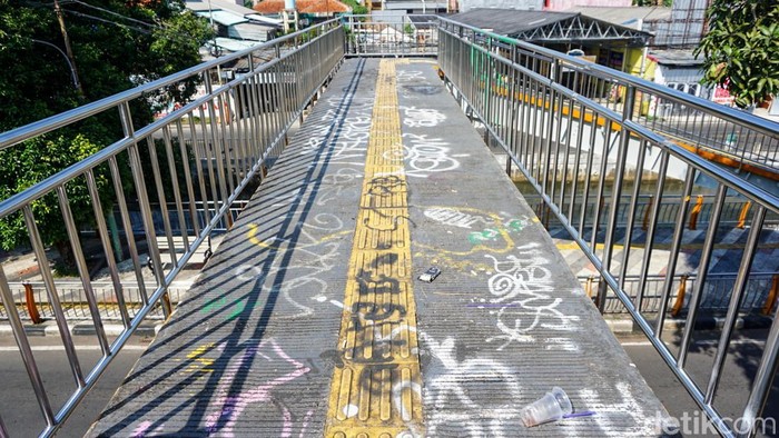 Aksi vandalisme terlihat pada fasilitas umum di kawasan Taman Secawan, Depok, Kamis (21/05/2026).  Lantai jembatan penghubung dipenuhi coretan grafiti dan tulisan menggunakan cat semprot.