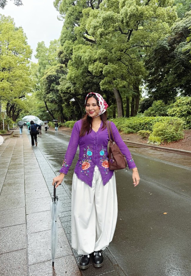 Indah tampil memukau dengan kebaya modern warna ungu. Kebaya tersebut memiliki model fitted di bagian tubuh sehingga memberi siluet ramping. Ia memadukan kebaya tersebut dengan celana kulot longgar warna putih gading. Foto: Instagram/@arie_kriting