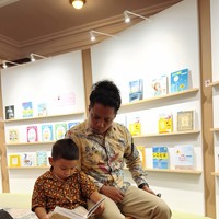 Naka tampak asik membaca buku ditemani ayahnya saat berada di museum tersebut. Foto: Instagram/@arie_kriting