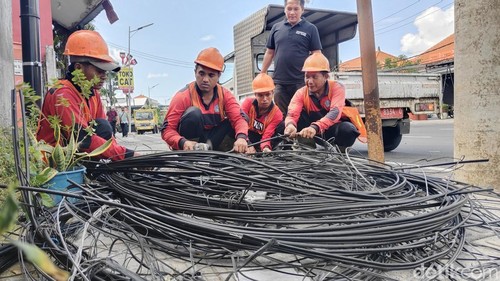 Petugas Dinas PUPR bersihkan kabel optik tak terpakai di ruas Jalan Teuku Umar Barat, Kuta Utara, Badung, Jumat (22/5/2026). (Agus Eka/detikBali)